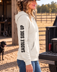 The Branded Zip in Oatmeal Heather — female model, side view showing SADDLE SIDE UP sleeve print